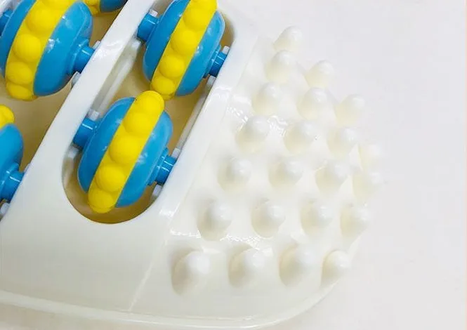 White dual foot acupressure massager roller for plantar fasciitis relief, with textured plastic surface
