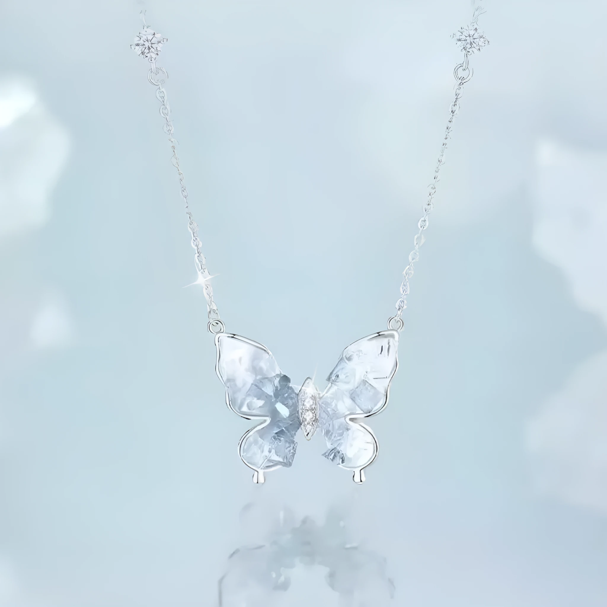 Close-up of a silver necklace with a detailed ice rain butterfly pendant on an O-ring chain.
