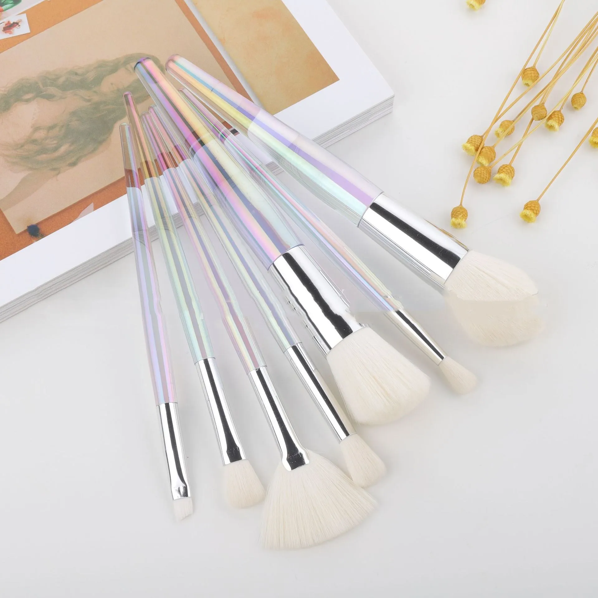 Water drop pattern makeup brush set of seven brushes with blue gold pink purple and transparent handles on white background
