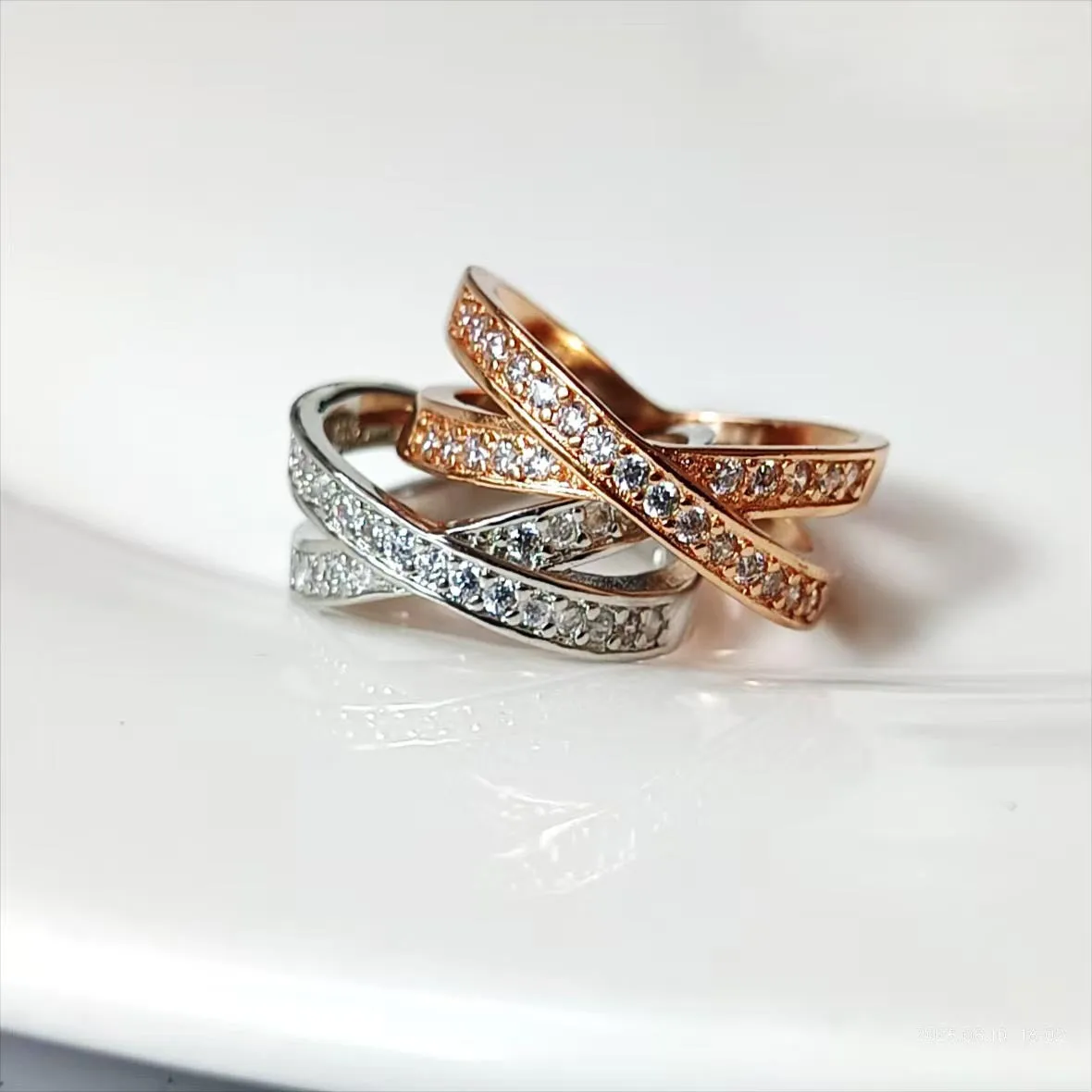Silver or rose gold metal cross ring with micro-inlaid zircon accents on a plain background.