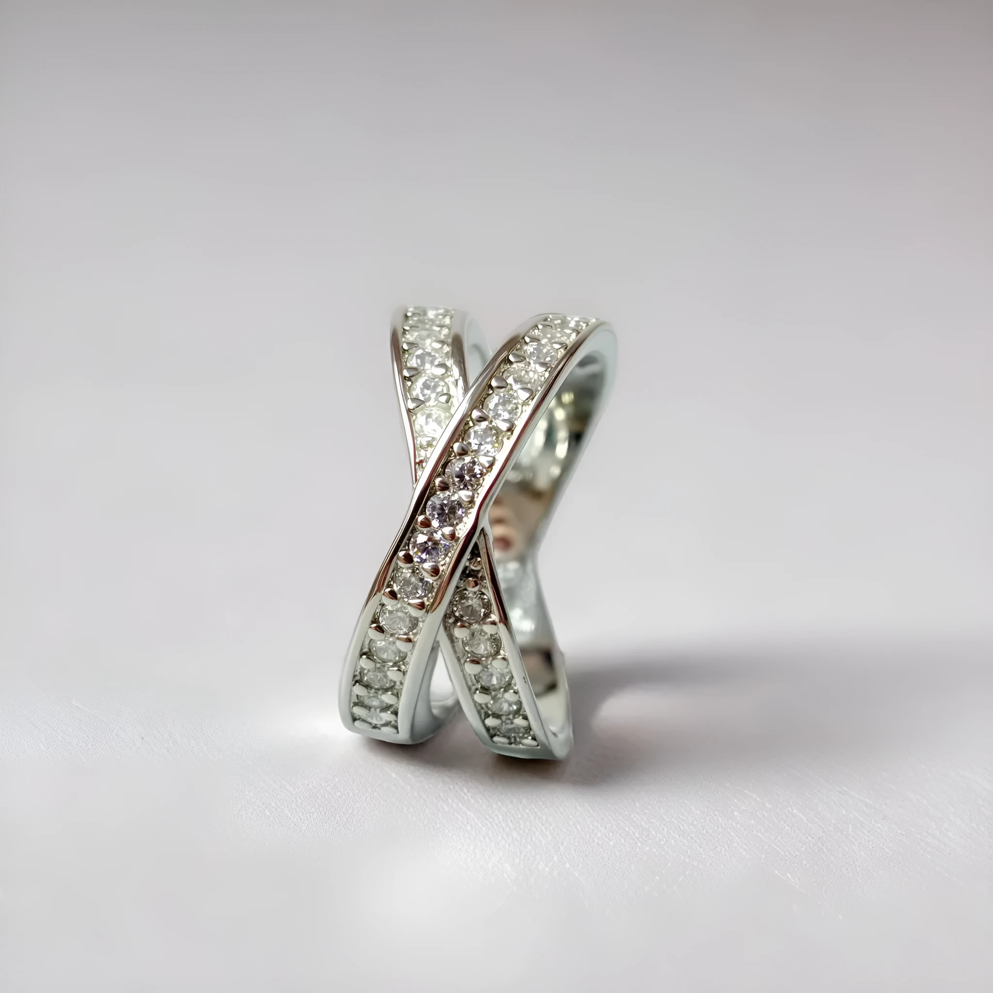 Silver or rose gold metal cross ring with micro-inlaid zircon accents on a plain background.