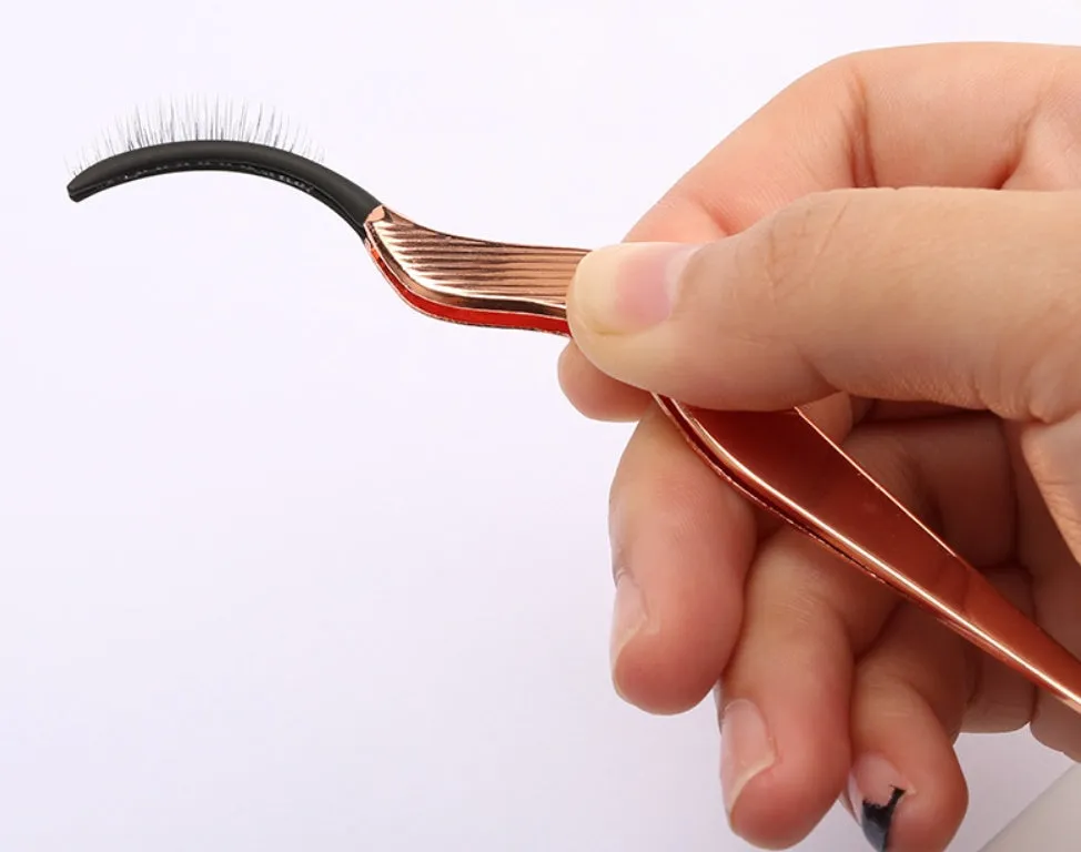 Rose gold metal false eyelash curler aid tool on plain background