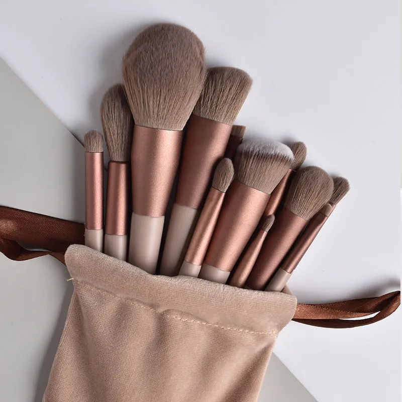Thirteen Morandi green makeup brushes laid out, including blush and powder brushes