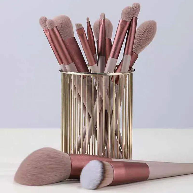 Thirteen Morandi green makeup brushes laid out, including blush and powder brushes