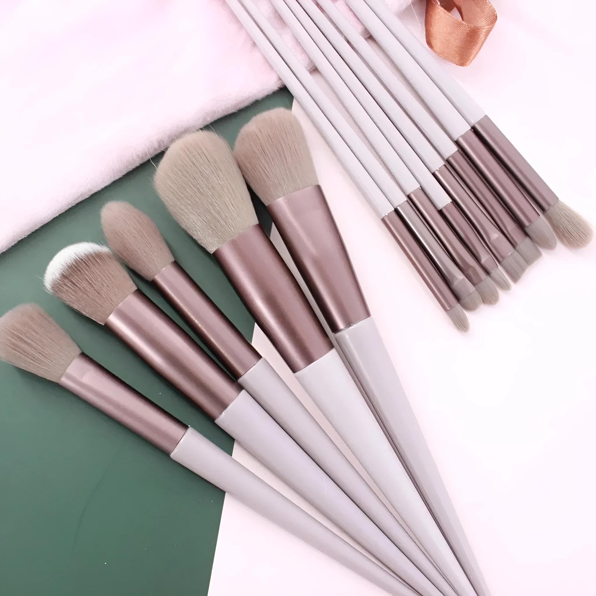 Thirteen Morandi green makeup brushes laid out, including blush and powder brushes