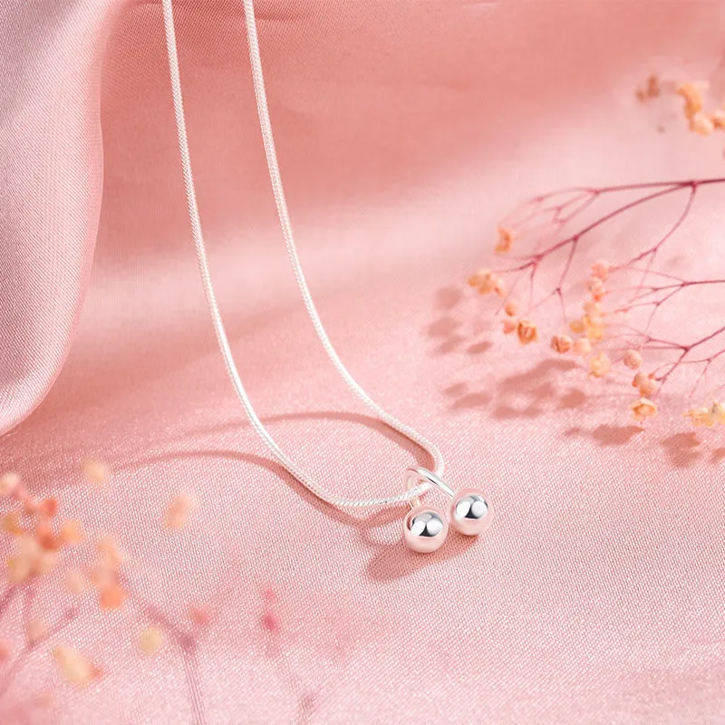 Silver cherry necklace for women with adjustable snake bone chain on a grey background.