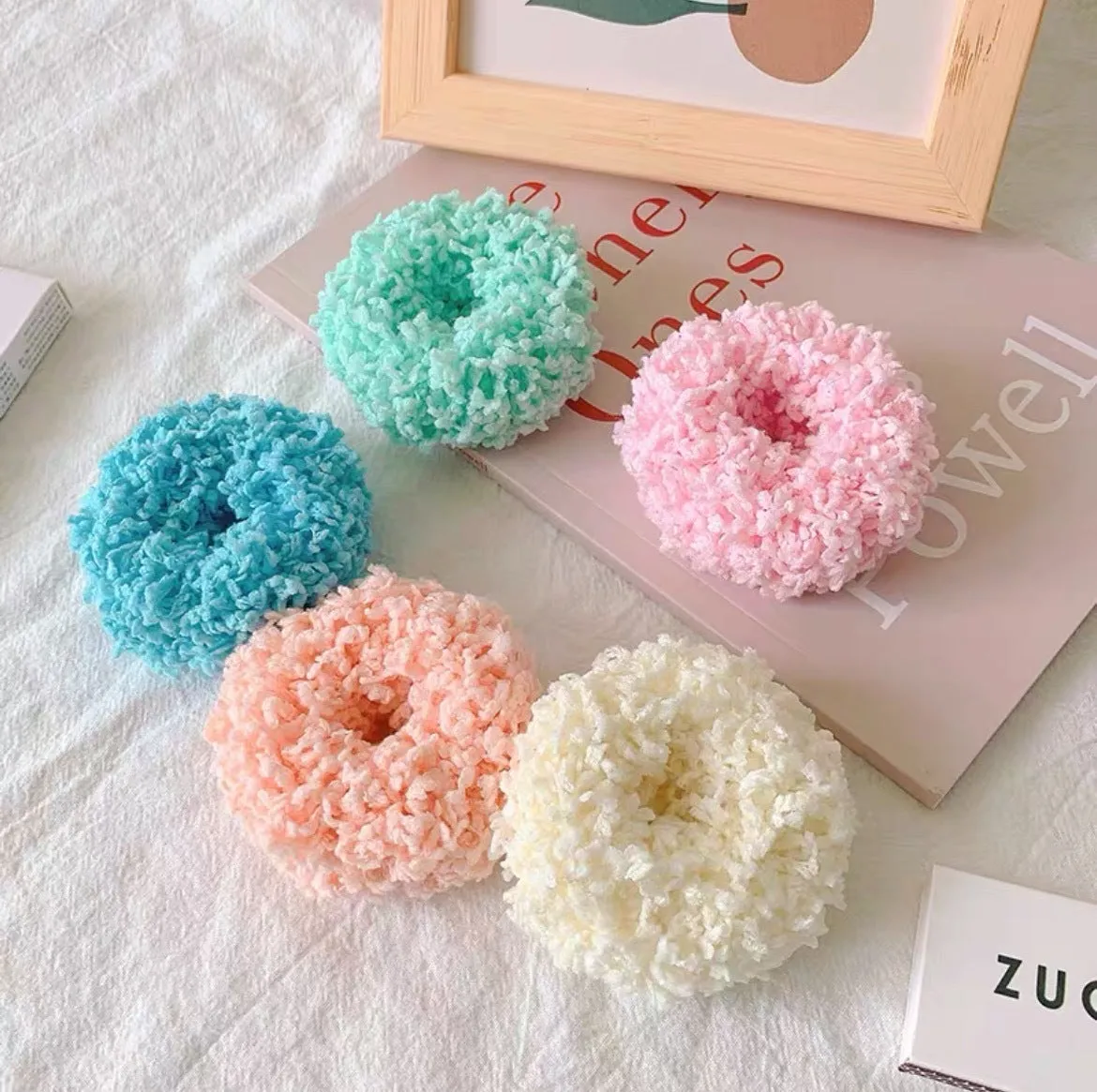 Seven luminous cloth hair ties in blue, pink, green, yellow, orange, purple, and white on a surface
