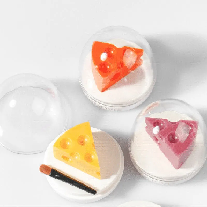 Pink cheese-shaped lip balm with Vitamin E and cream scent in open case with brush applicator