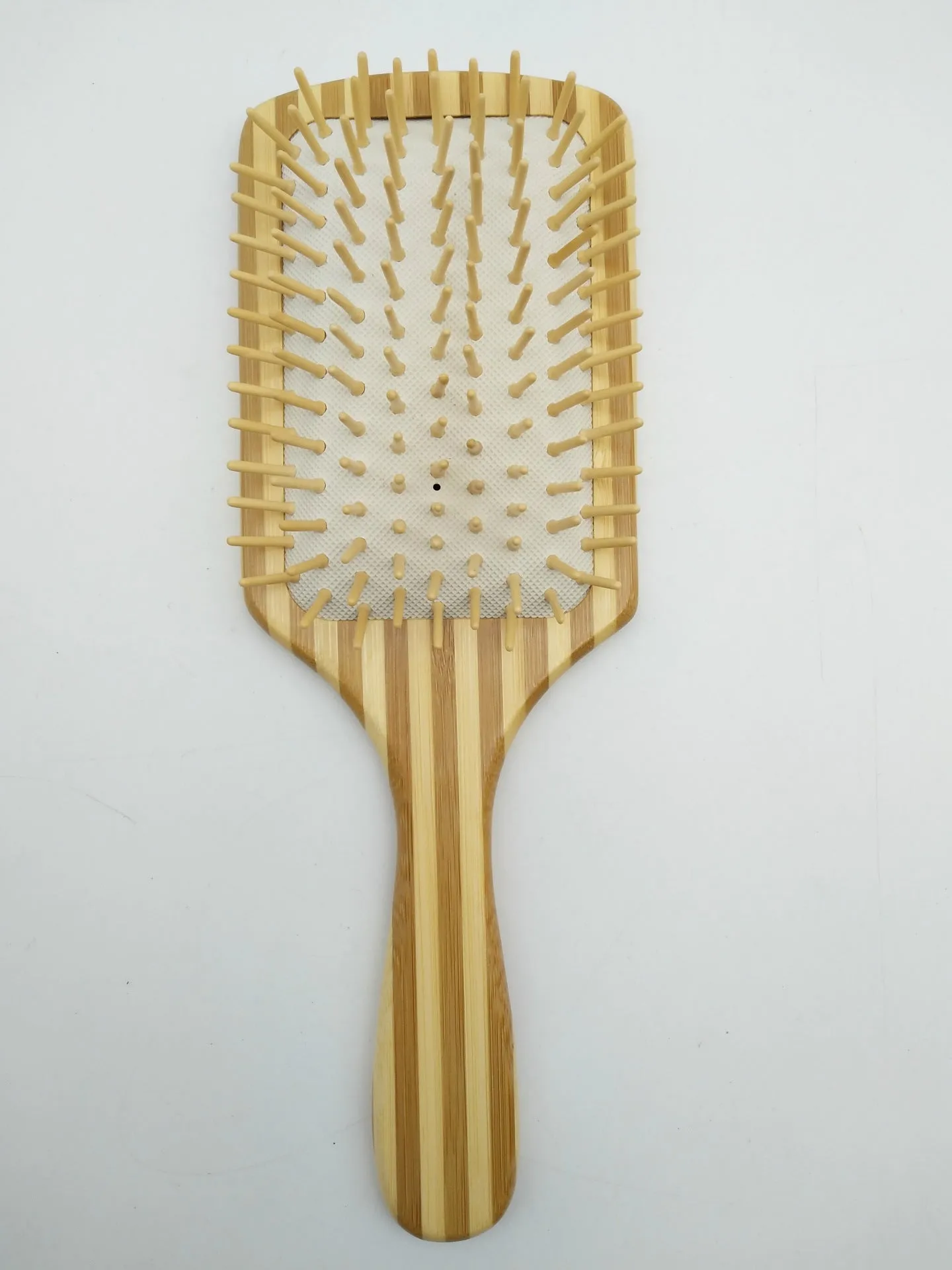 Natural bamboo scalp massage comb with round nylon teeth and rubber pad on neutral background