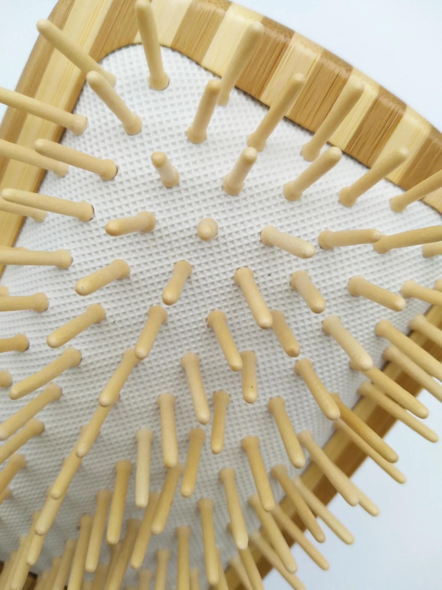 Natural bamboo scalp massage comb with round nylon teeth and rubber pad on neutral background