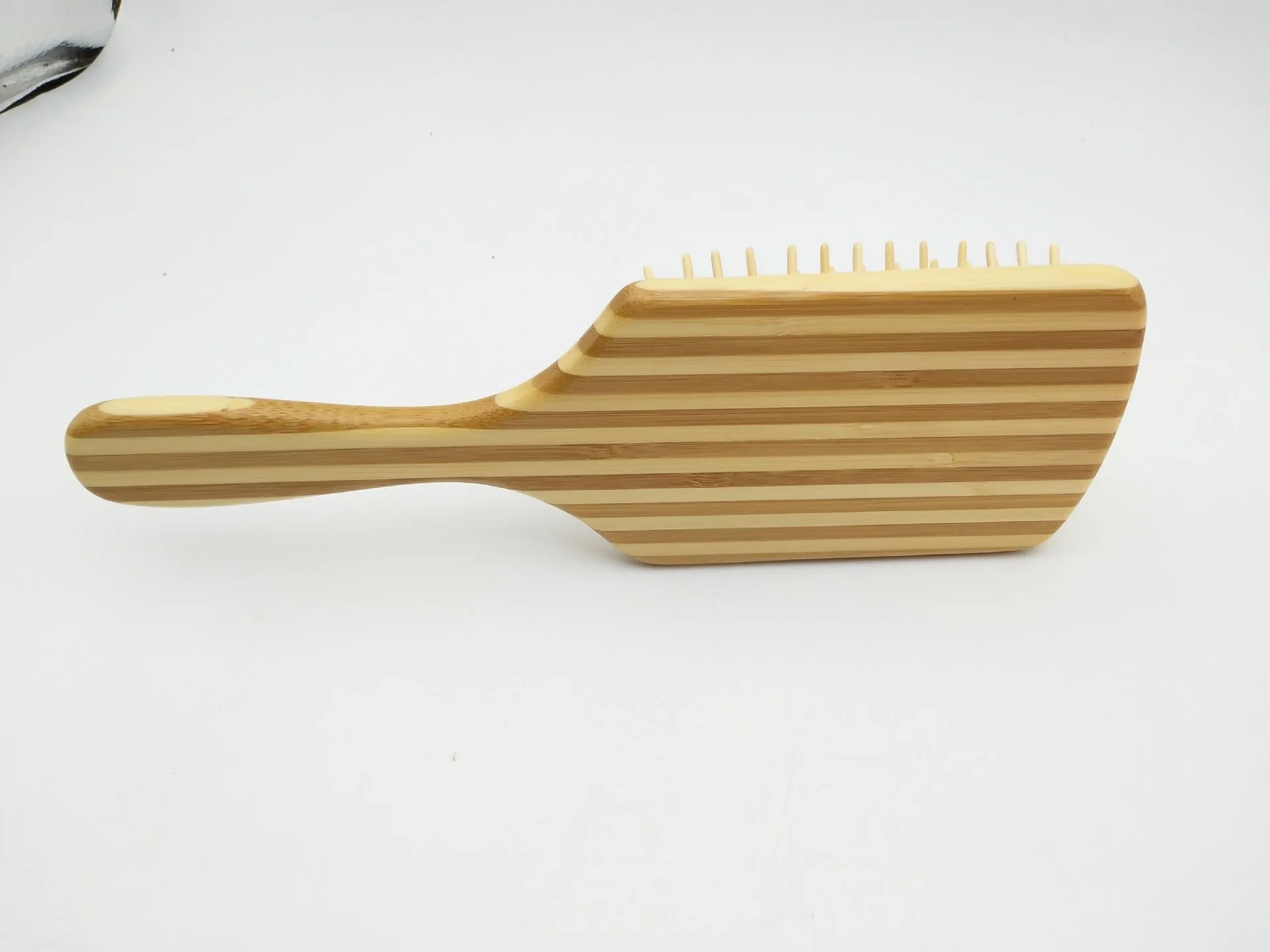 Natural bamboo scalp massage comb with round nylon teeth and rubber pad on neutral background