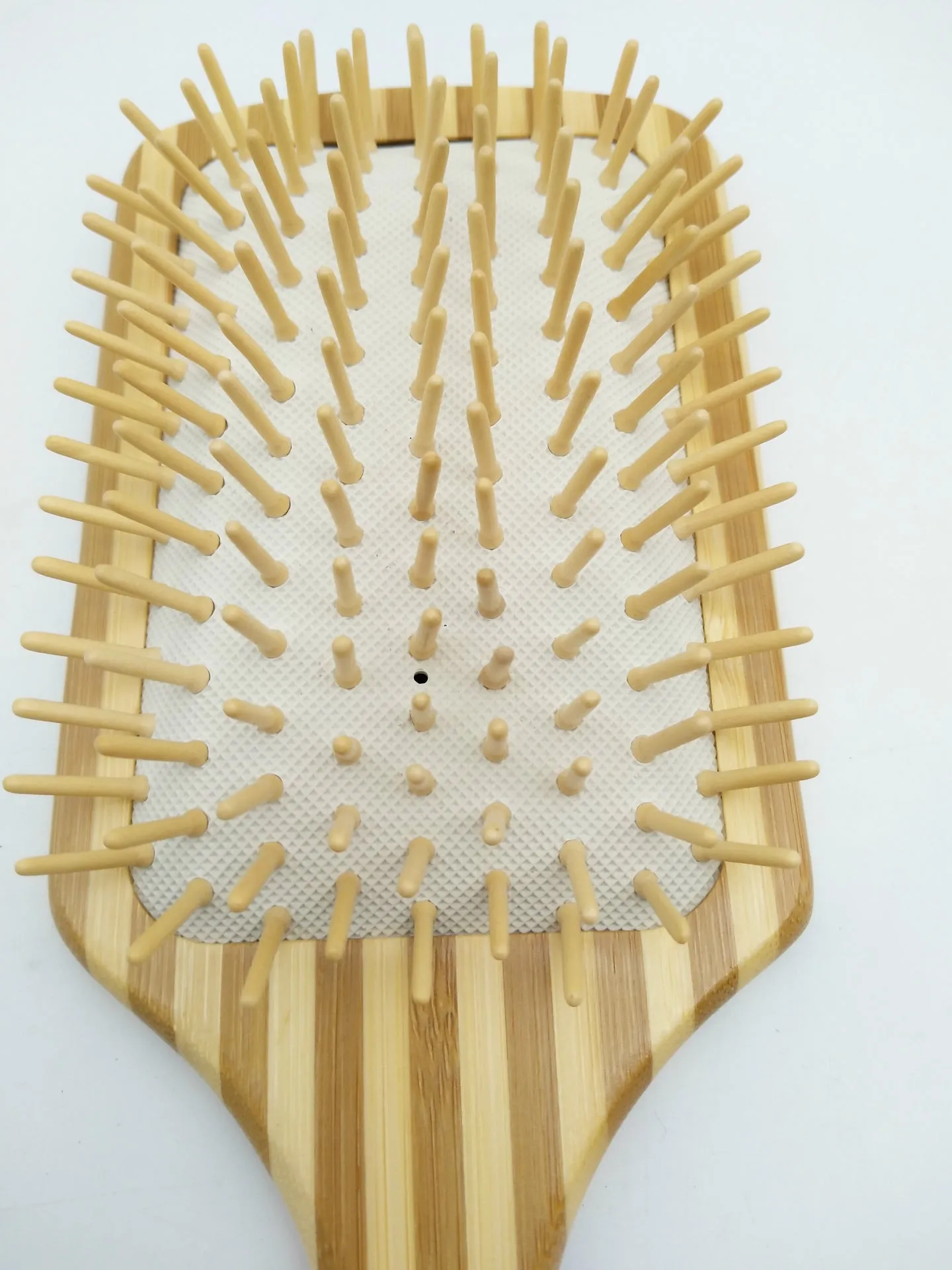 Natural bamboo scalp massage comb with round nylon teeth and rubber pad on neutral background