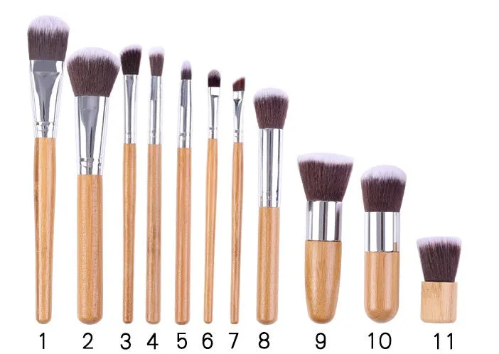 11 bamboo handle makeup brushes arranged on linen bag, including foundation blush and eye shadow brushes