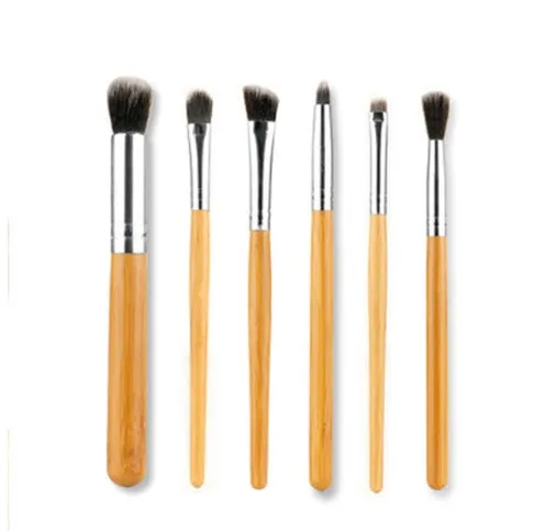 11 bamboo handle makeup brushes arranged on linen bag, including foundation blush and eye shadow brushes