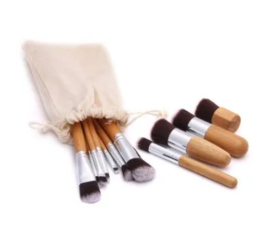 11 bamboo handle makeup brushes arranged on linen bag, including foundation blush and eye shadow brushes