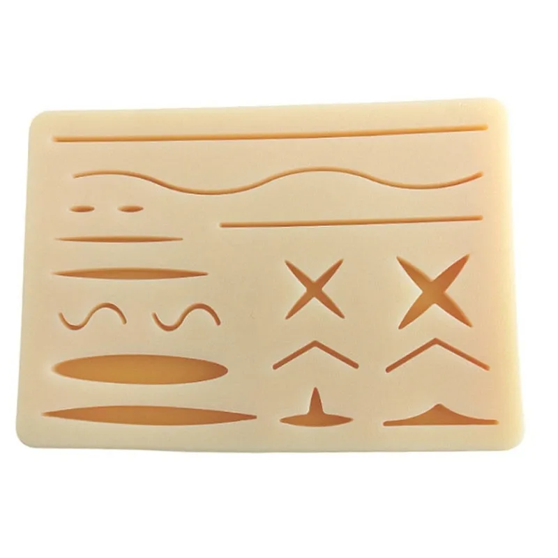 Medical student training kit with black silicone suture pad, tools, and multi-wound block on a table