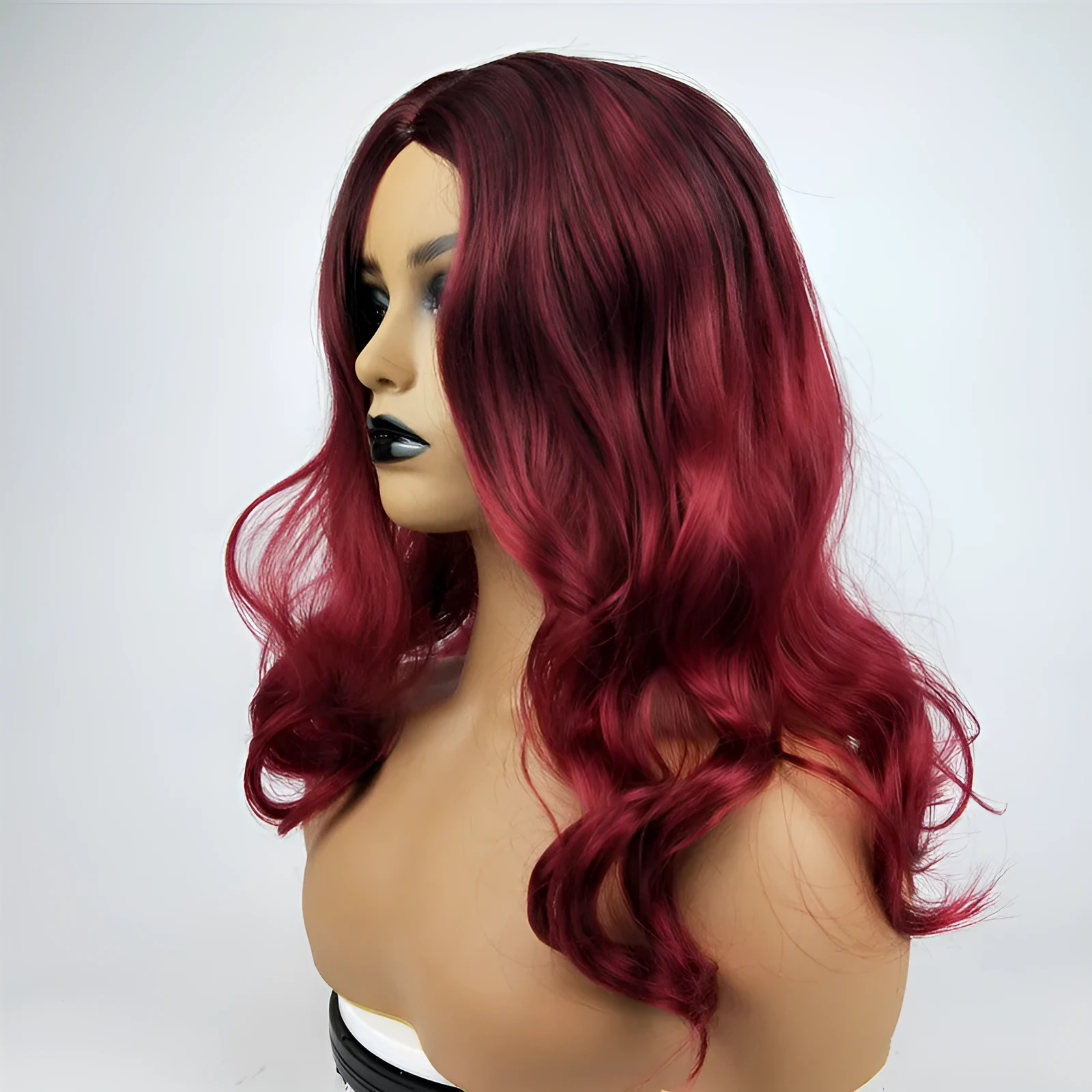 Burgundy long curly wig with gradient colour and centre bangs on a wig stand