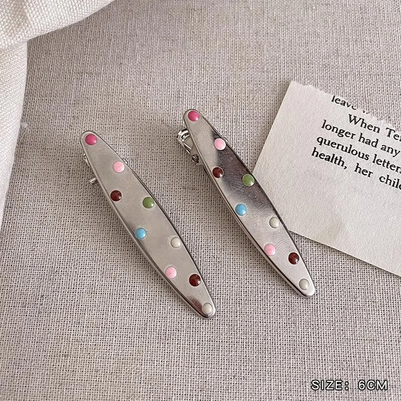 Two shiny silver metal duckbill barrettes with hollow star patterns on a plain background