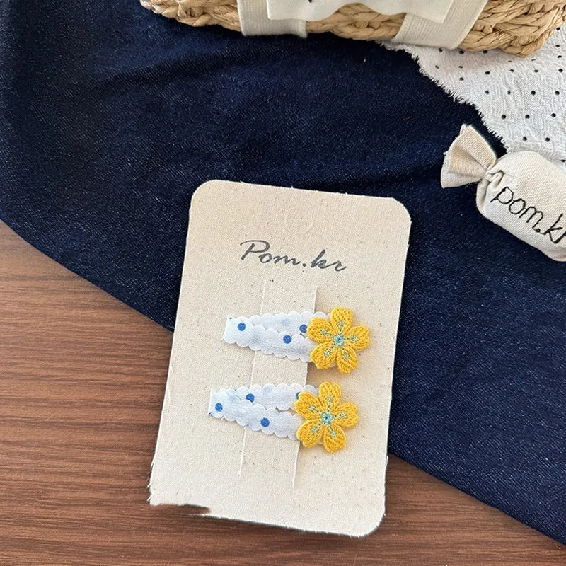 Children's denim handmade flower polka dot bow barrettes with triangle and duckbill clips on a light background