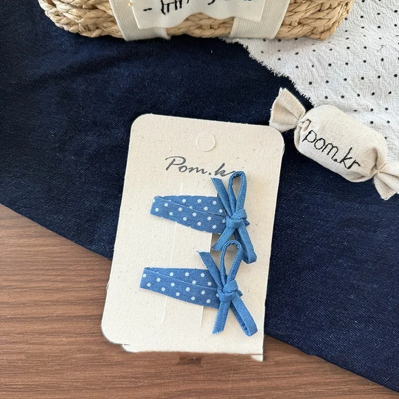 Children's denim handmade flower polka dot bow barrettes with triangle and duckbill clips on a light background