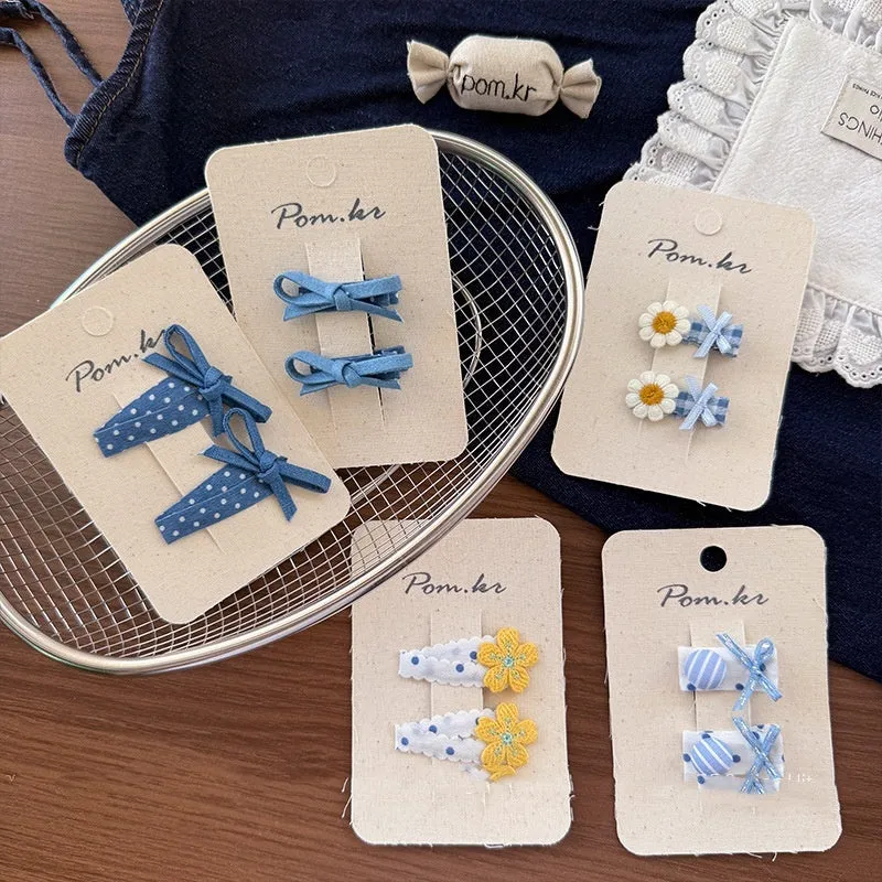 Children's denim handmade flower polka dot bow barrettes with triangle and duckbill clips on a light background