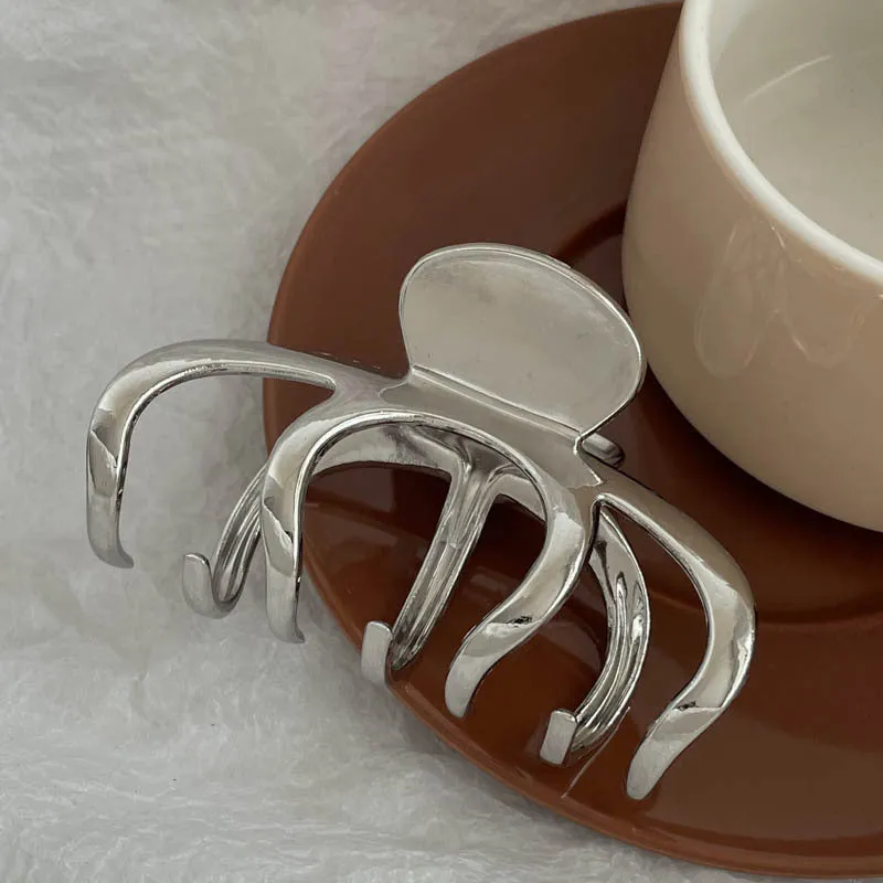 Assortment of silver metal hair barrettes and claw clips in various Korean-style designs on a white background.