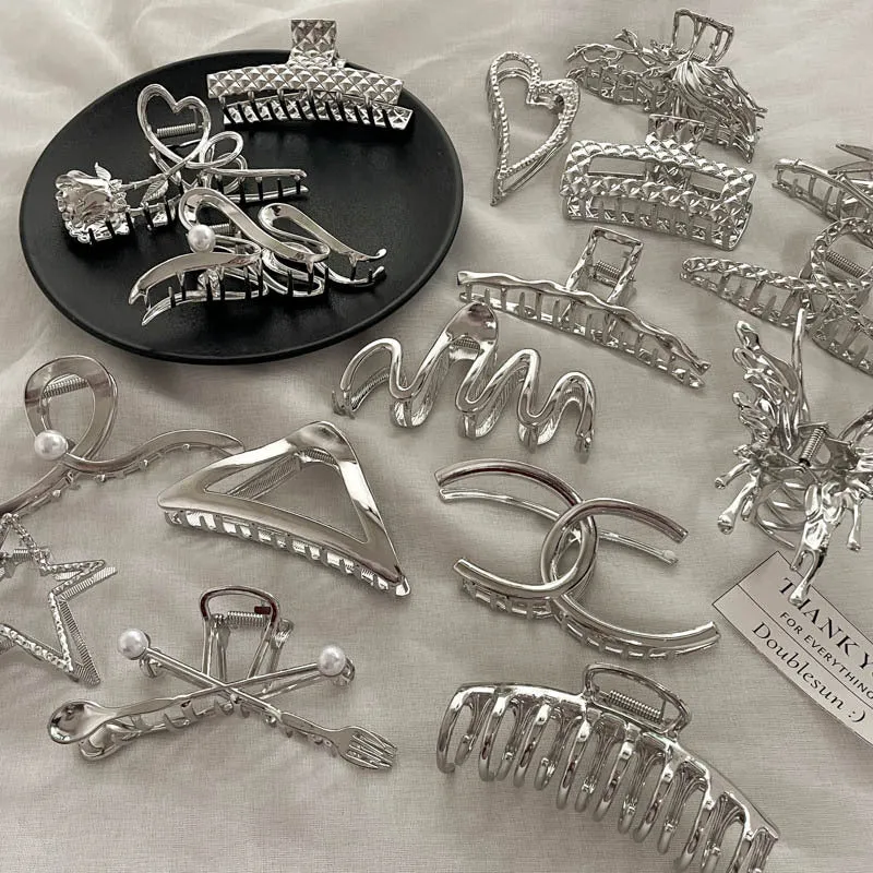Assortment of silver metal hair barrettes and claw clips in various Korean-style designs on a white background.