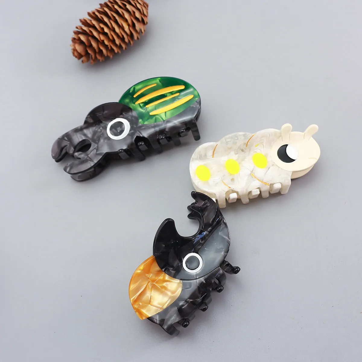 Handmade cellulose acetate beetle grip accessory with cartoon insect biology design in green or orange colour