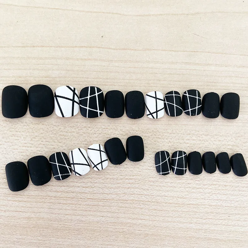 Fake nail patch with matte black and white lines design on a white background