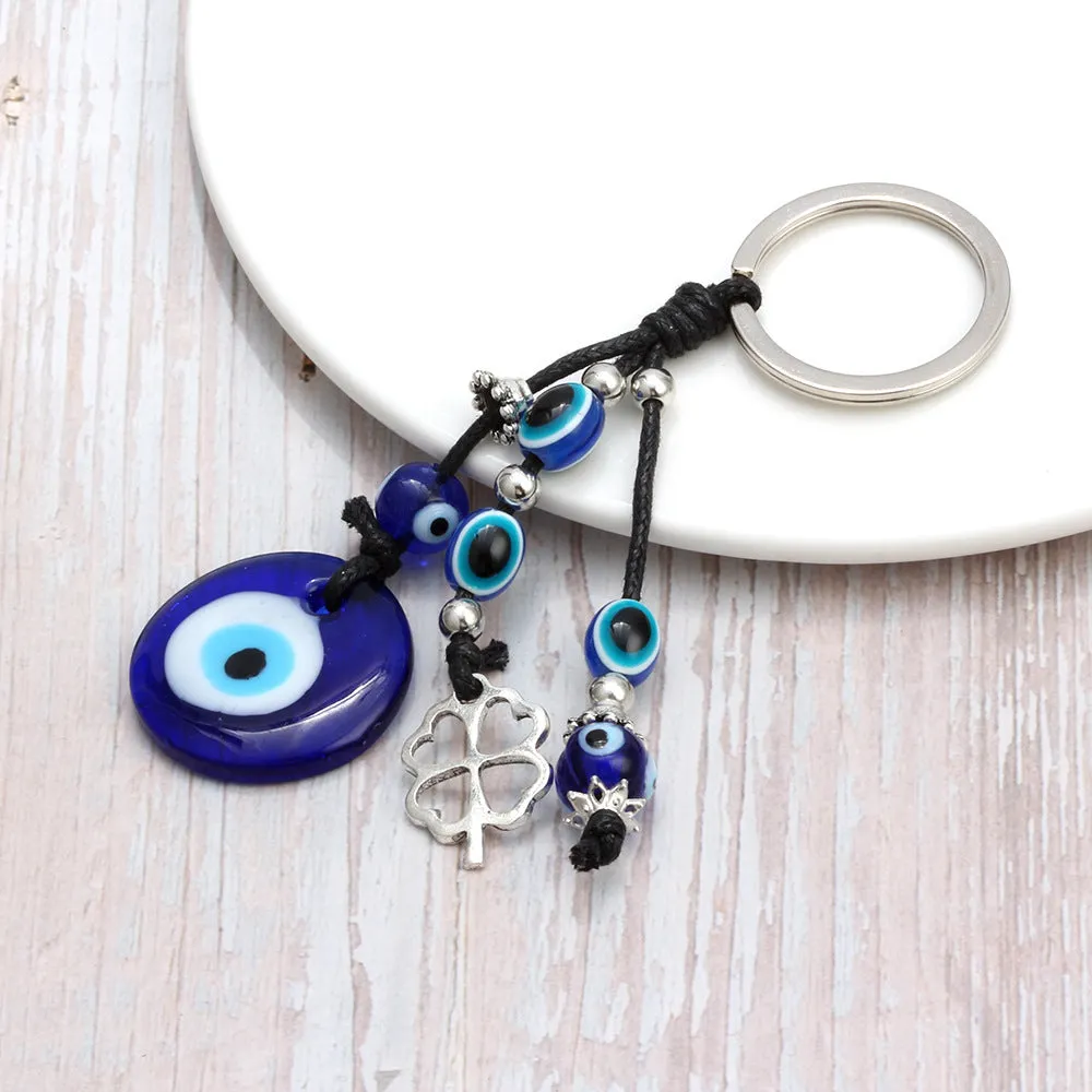 Blue metal eye of evil keychain 4cm pendant with plant-inspired design on grey background
