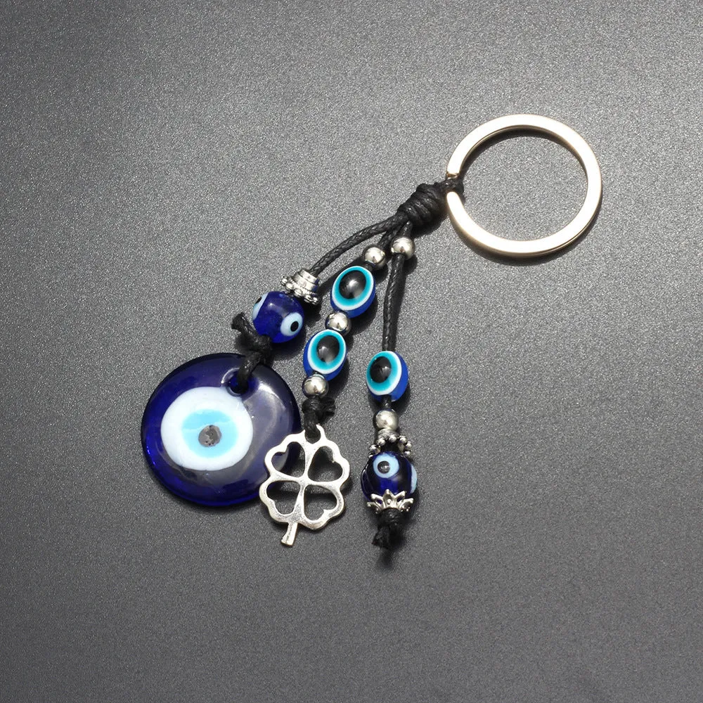 Blue metal eye of evil keychain 4cm pendant with plant-inspired design on grey background