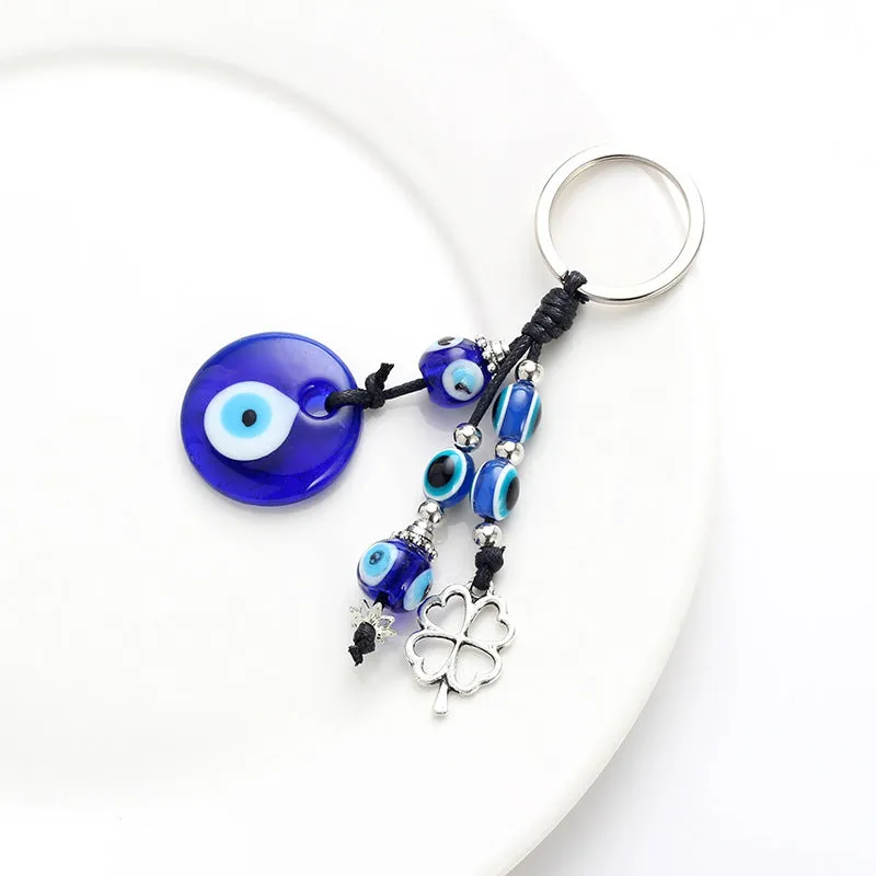 Blue metal eye of evil keychain 4cm pendant with plant-inspired design on grey background