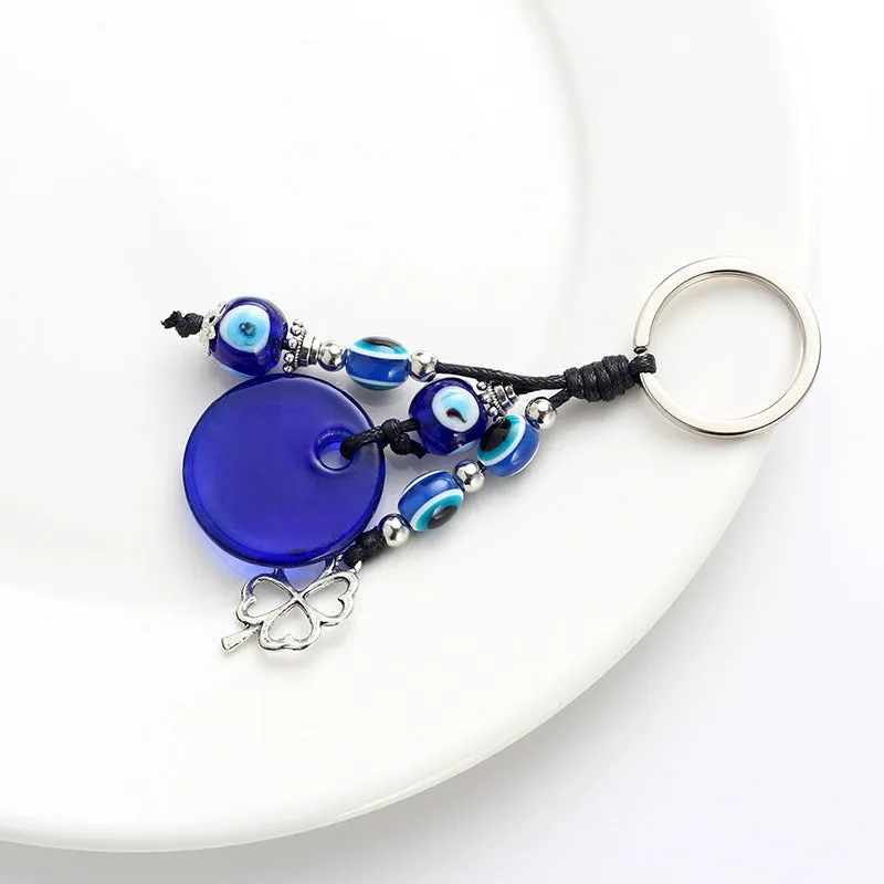 Blue metal eye of evil keychain 4cm pendant with plant-inspired design on grey background