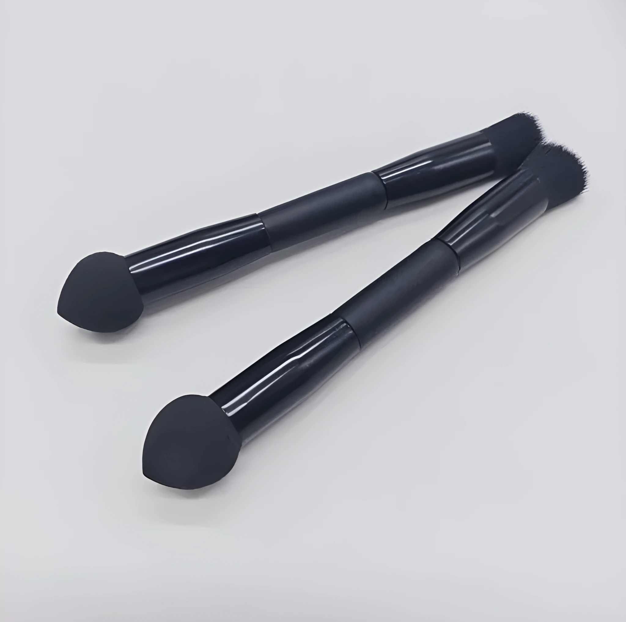 Double-headed concealer brush with black wooden handle, artificial fibre bristles, and angled sponge tip.