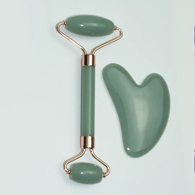 Stainless steel double-headed facial roller, heart-shaped acupressure stick, and scraping plate on a white background.