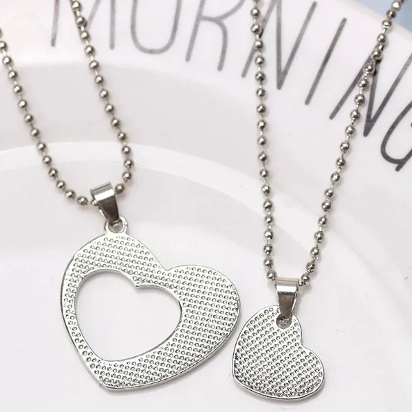 Two silver alloy heart-shaped puzzle necklaces on cross chains, matching set
