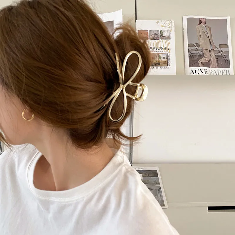 Close-up of a women's gold alloy hair barrette with a bow design and secure clip.