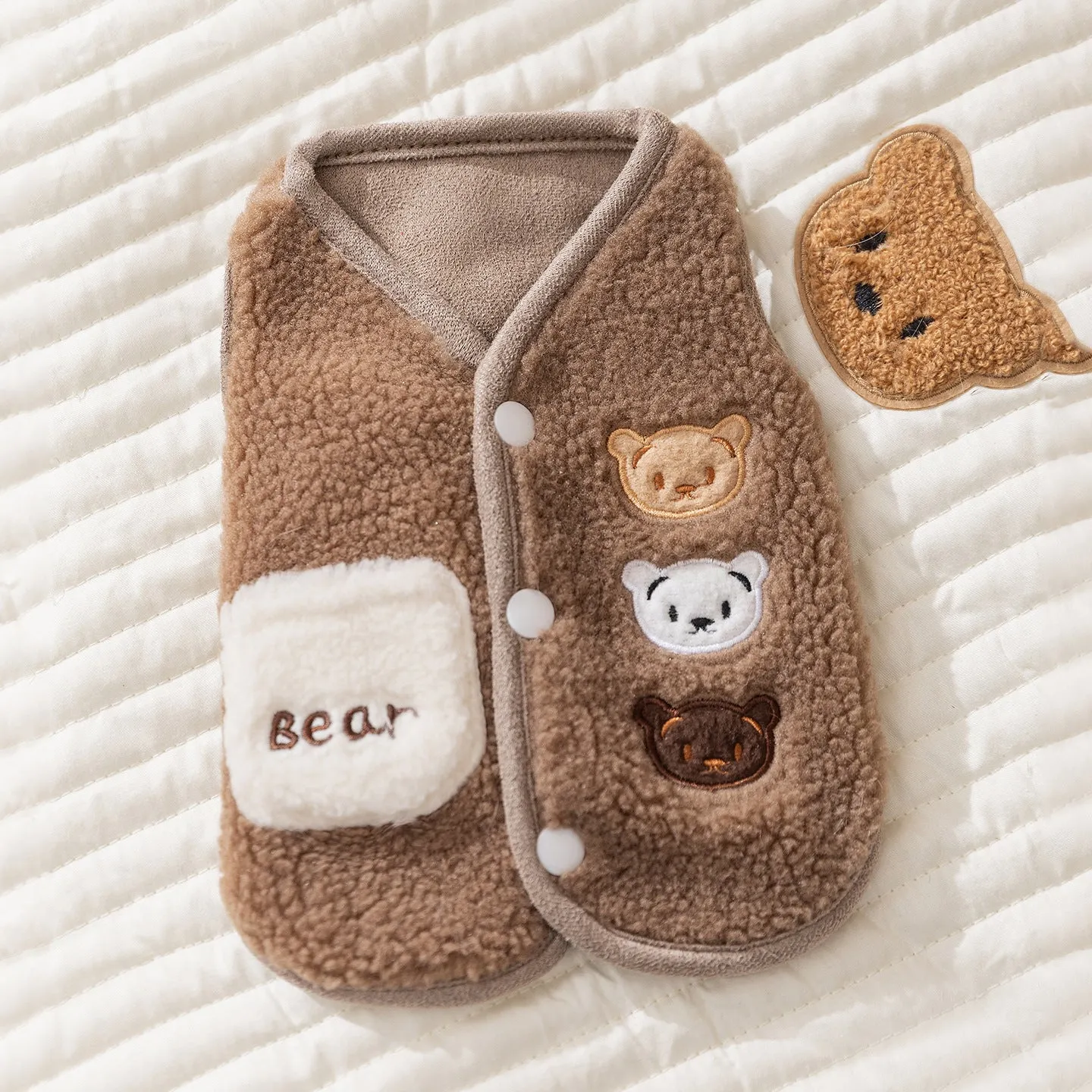 Brown fleece dog coat with bear embroidery and side-button closure on a small dog