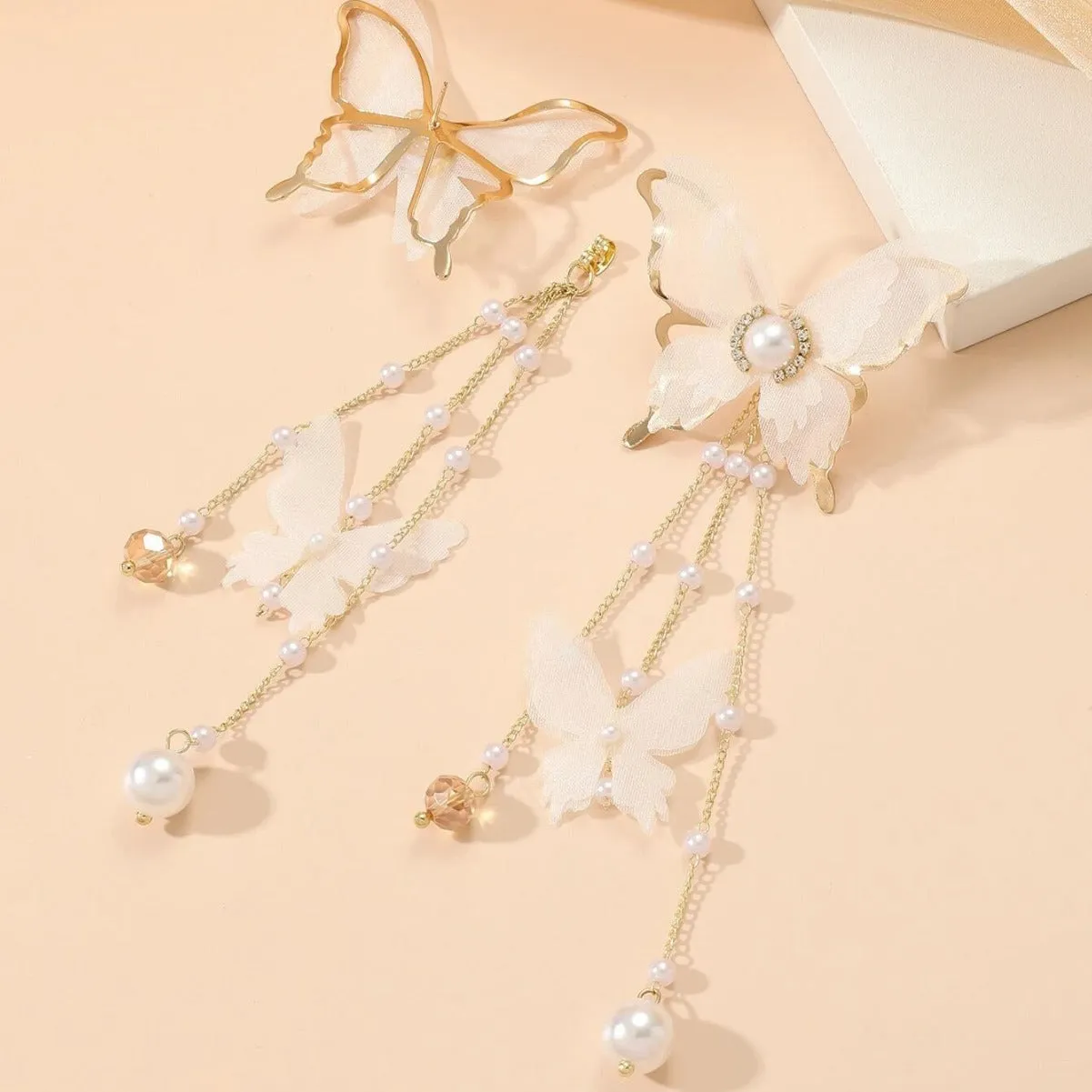 A pair of white butterfly-shaped earrings with tassel lace, pearls, and clear rhinestones on a copper alloy base.