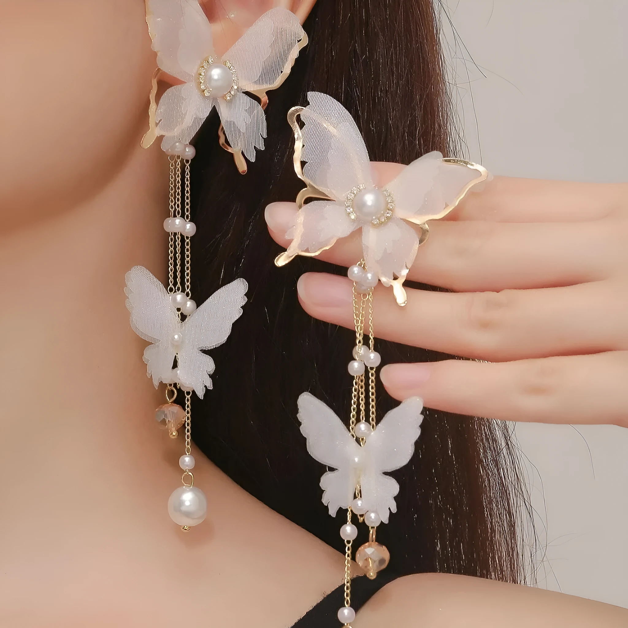 A pair of white butterfly-shaped earrings with tassel lace, pearls, and clear rhinestones on a copper alloy base.