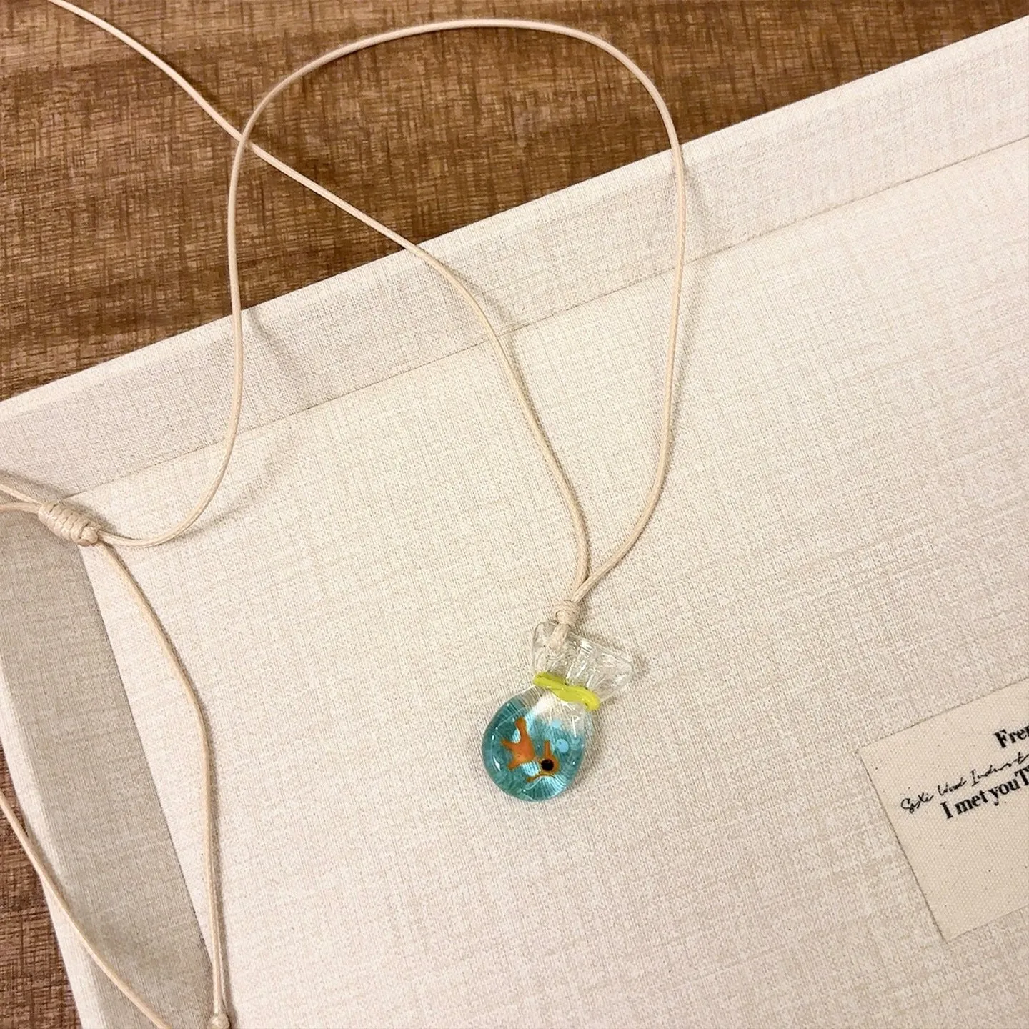 Women's joker pendant necklace with coloured glaze charm on a cotton and linen clavicle chain.
