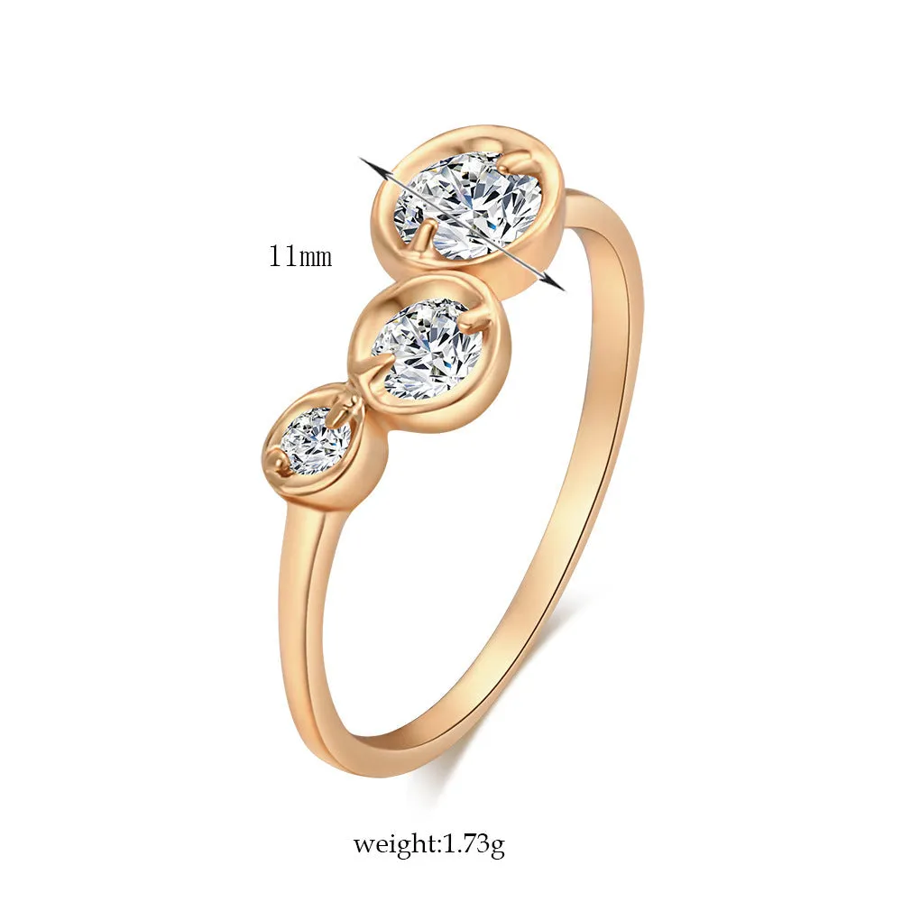 Three copper electroplated rings with lotus leaf design and round zircon stones in gold white zirconium tone on a flat surface