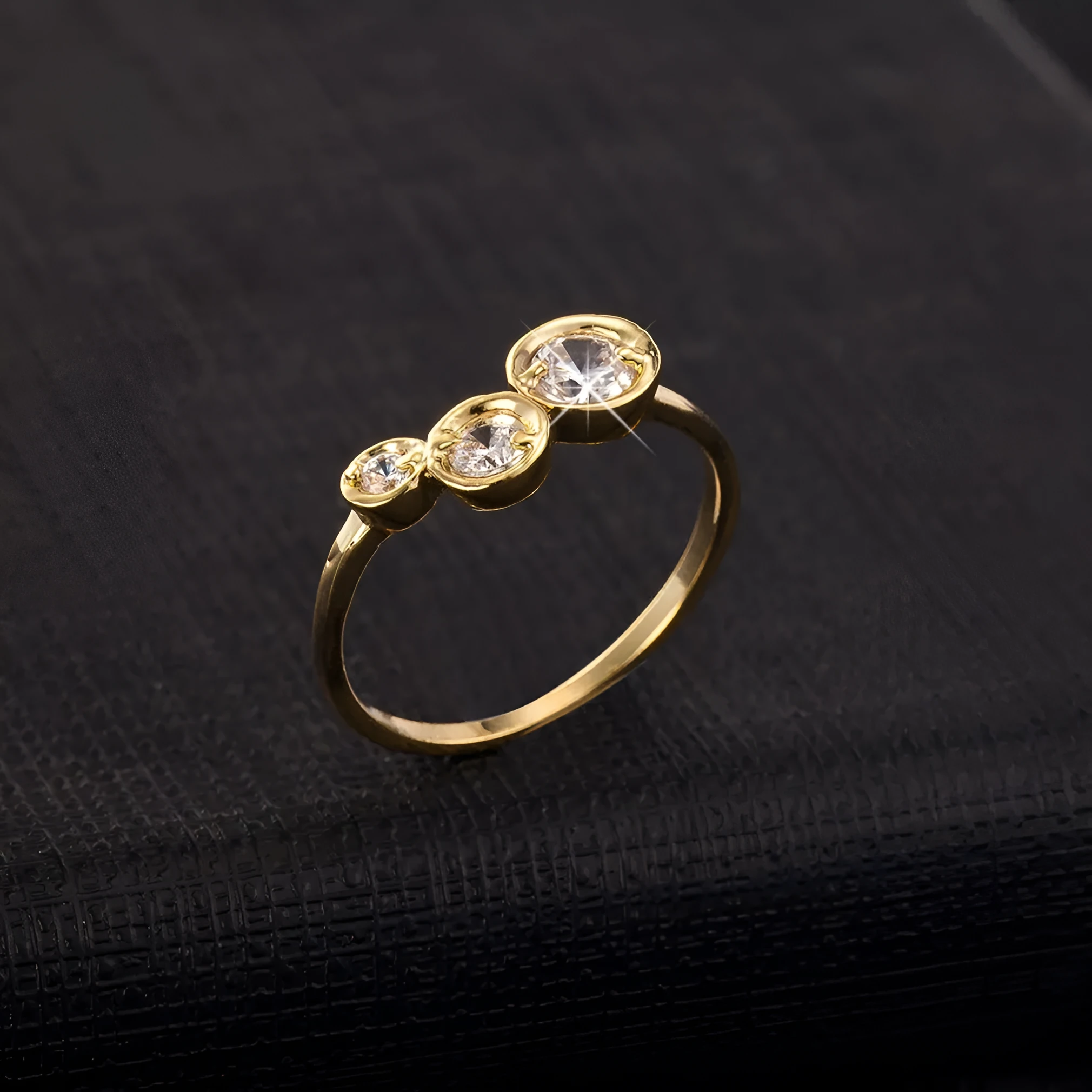 Three copper electroplated rings with lotus leaf design and round zircon stones in gold white zirconium tone on a flat surface