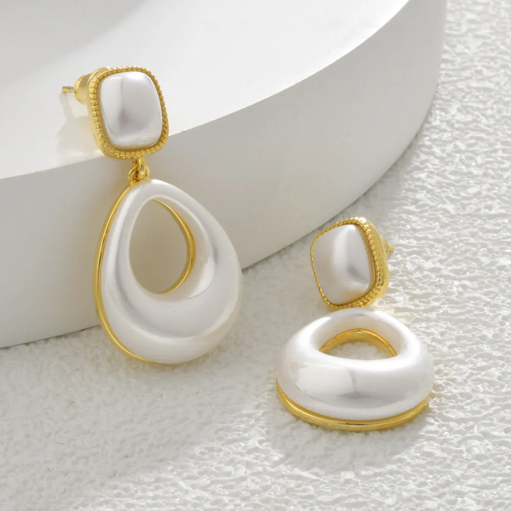 Gold coloured drop shaped earrings with a central imitation pearl, shown on a white background.