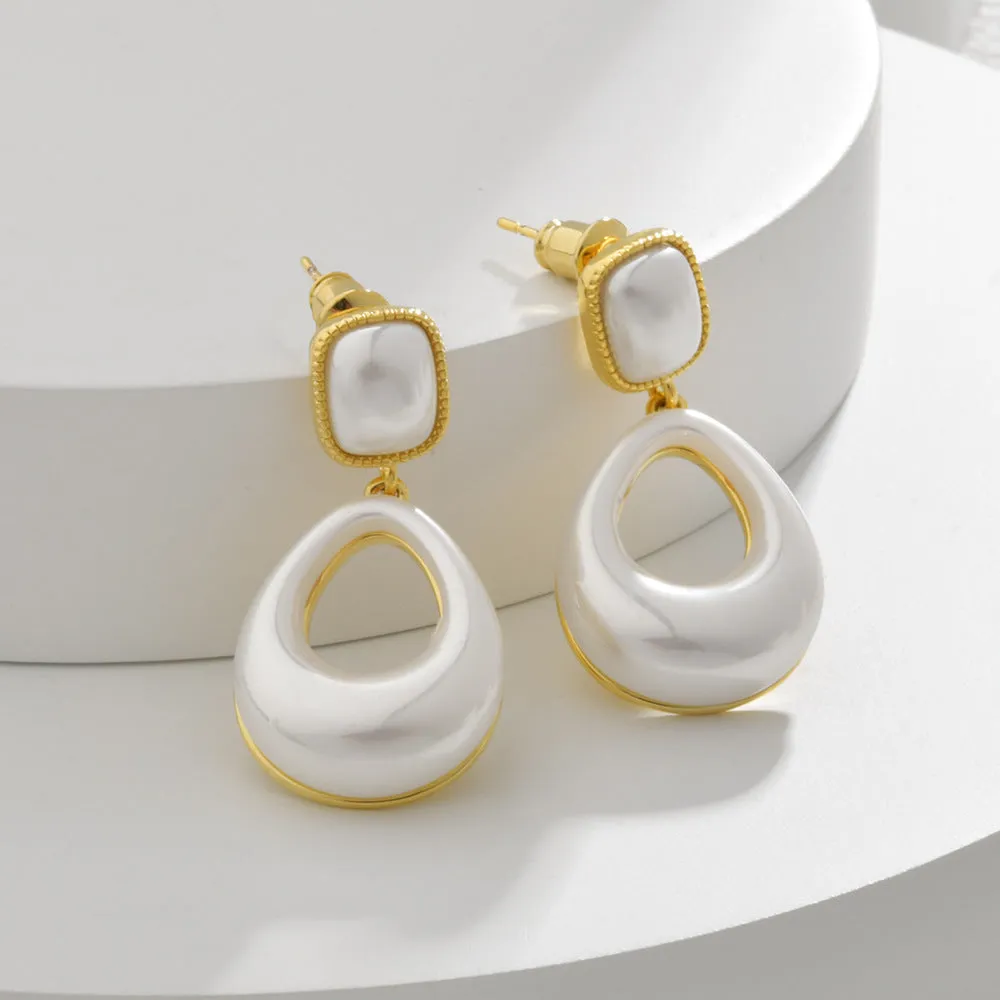 Gold coloured drop shaped earrings with a central imitation pearl, shown on a white background.