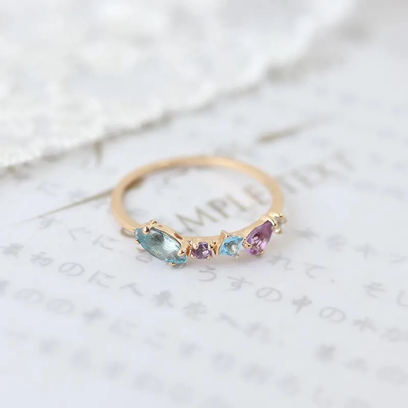 Gold-plated geometric ring with inlaid topaz and white amethyst stones on a white background