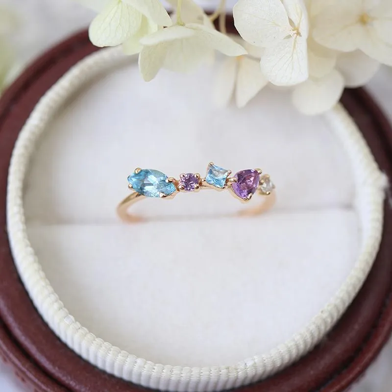Gold-plated geometric ring with inlaid topaz and white amethyst stones on a white background