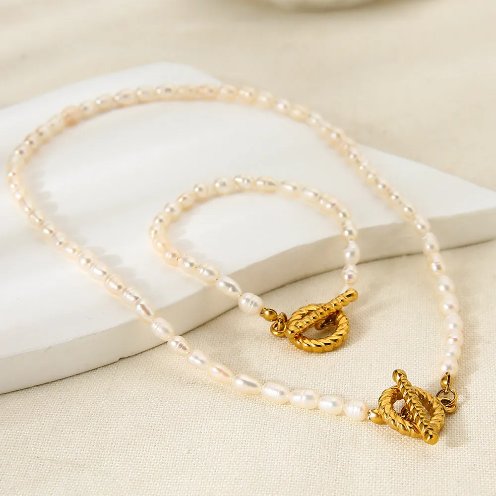 Women's freshwater pearl and geometric stainless steel necklace and bracelet set on a grey background