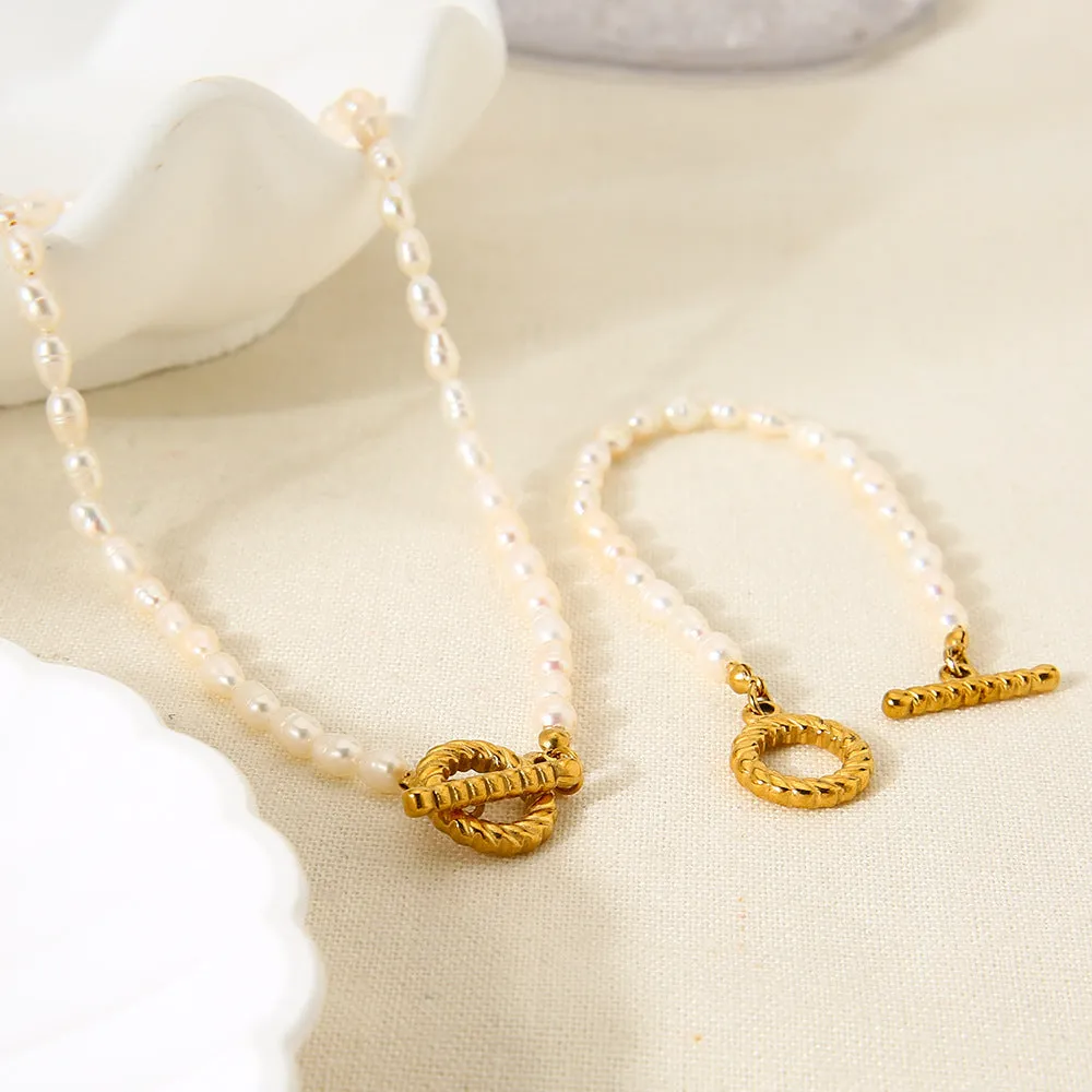 Women's freshwater pearl and geometric stainless steel necklace and bracelet set on a grey background