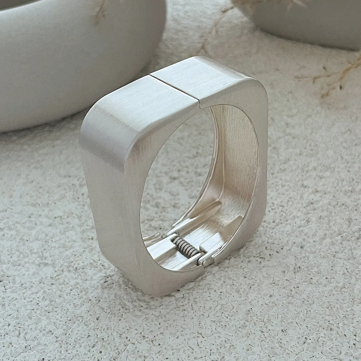 Metal texture glossy spring bracelet with geometric square mirror design in gold colour on white background